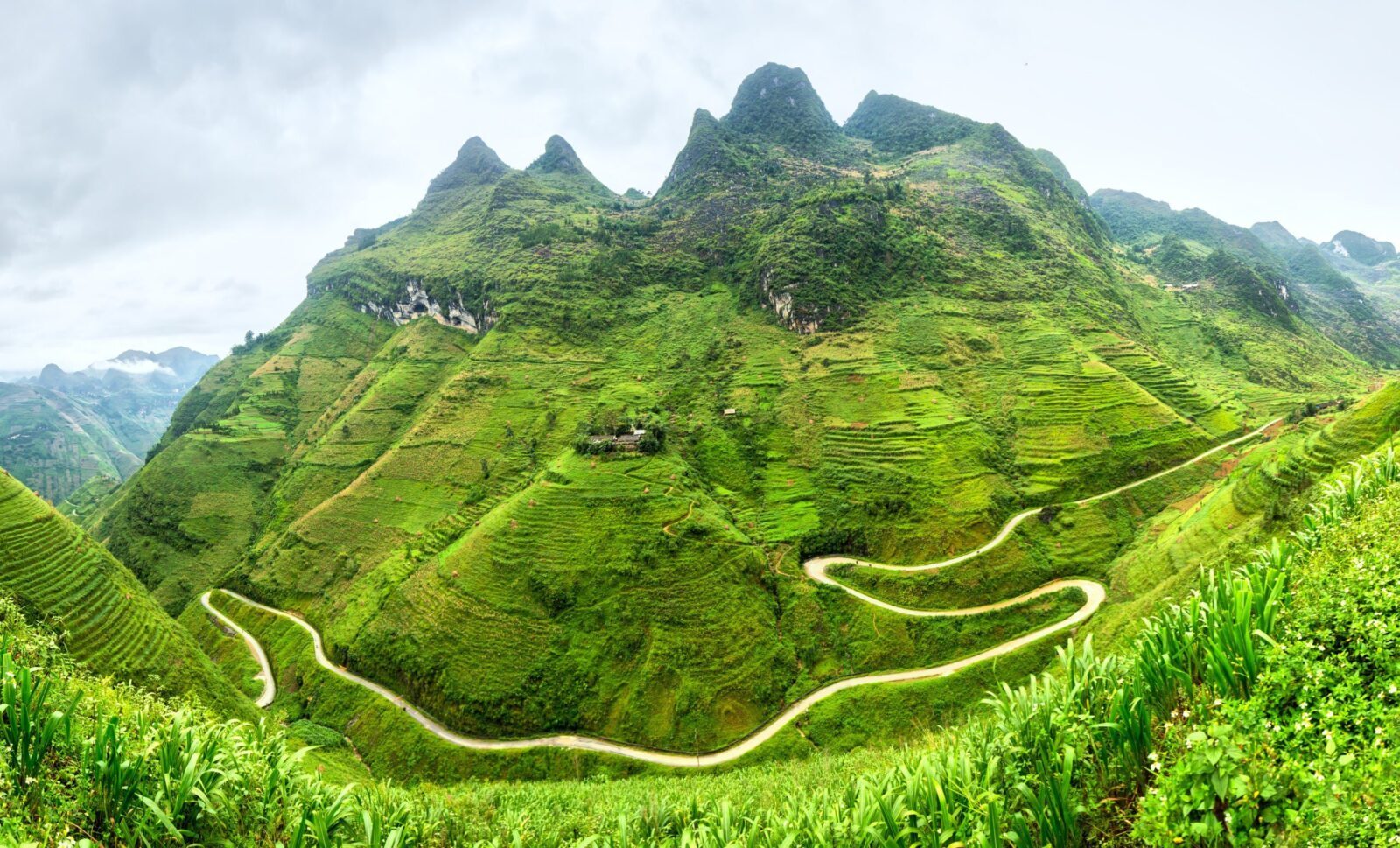 Road winding up a steep green mountainside in Ha Giang province, Vietnam