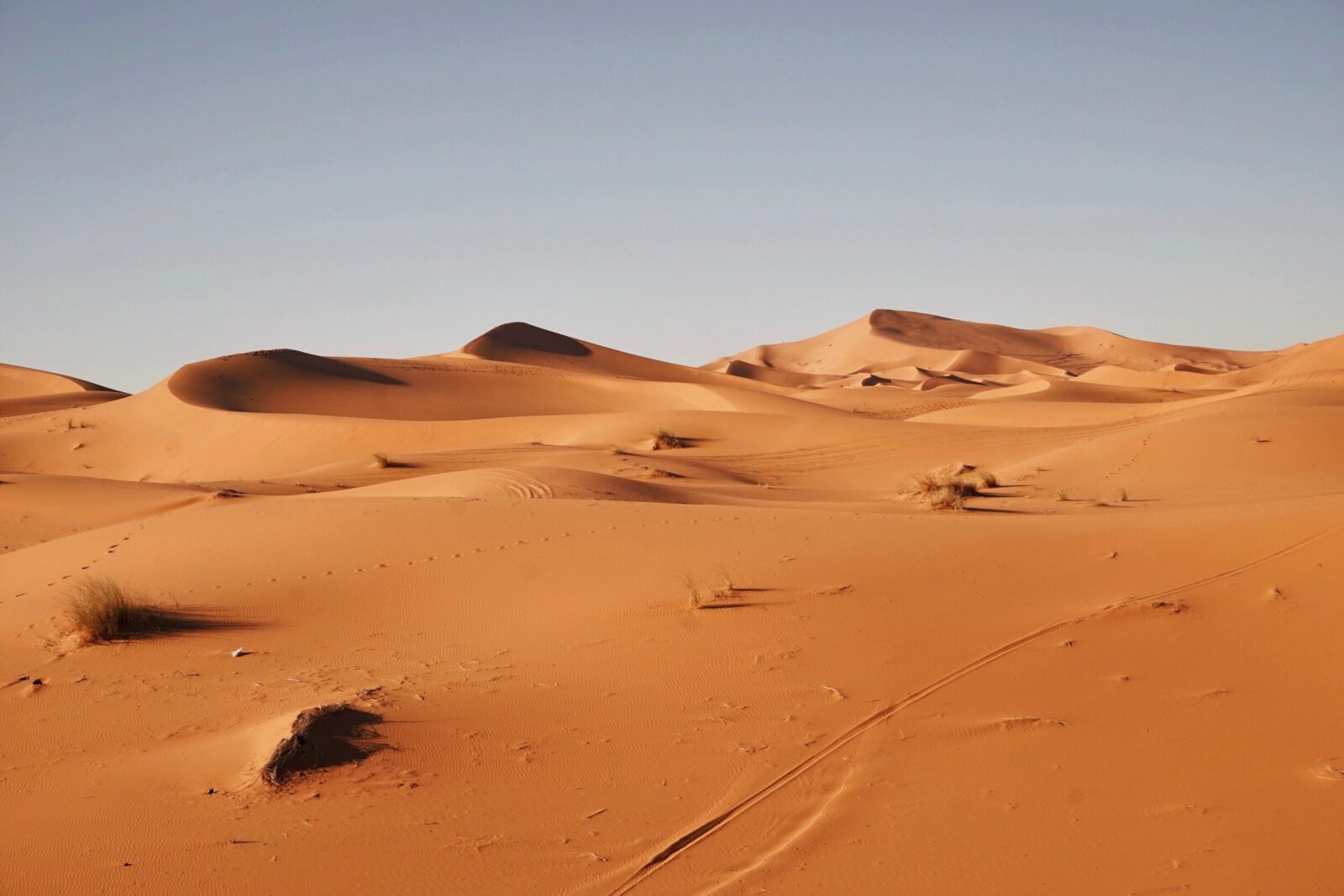 Orangefarbene Sanddünen der Sahara im Süden Marokkos unter blauem Himmel