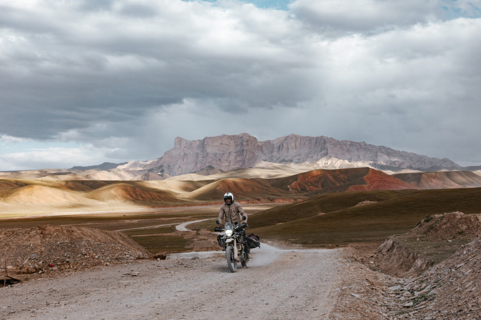 Moto sur une piste au milieu des badlands rouges, entre Tash Rabat et Kazarman