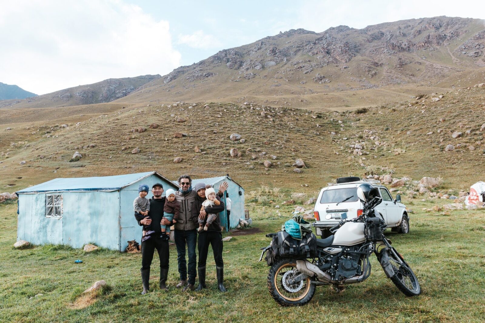 Famille kirghize devant une maison d'estive, à côté d'une moto Royal Enfield