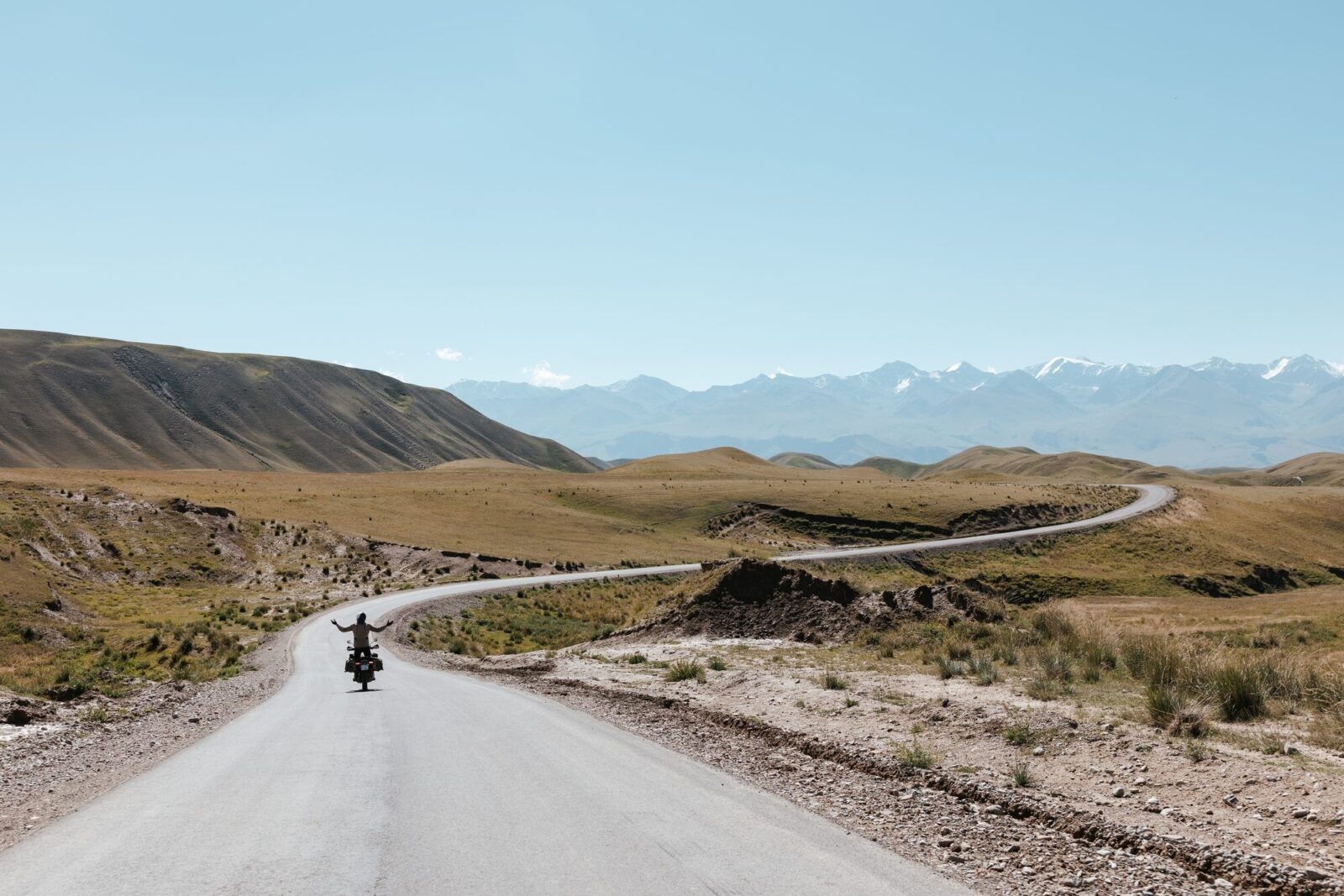 Route qui serpente vers les montagnes, road trip moto au Kirghizistan