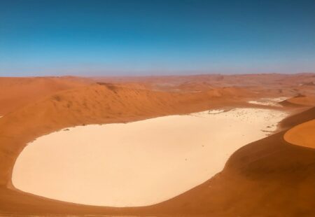 <h2>Sossusvlei, les plus hautes dunes du monde</h2>

Le temps passe si vite. Nous arrivons déjà à Sesriem, point de départ pour une excursion vers les dunes et le site incontournable de <a href="https://www.vintagerides.com/voyage-moto/namibie/pistes-en-terre-namibienne/">Sossusvlei</a>. Nous vivons un rêve qui dépasse tout ce que nous avions imaginé. A l’aube, nous grimpons au sommet de Big Daddy, considérée comme la plus haute dune du monde, culminant à 380 m de haut. On lève les yeux au ciel, à la fois émerveillés et impressionnés par l’ascension d’une  <a href="https://www.vintagerides.com/voyage-moto/namibie/pistes-en-terre-namibienne/">montagne de sable</a> plus haute que la Tour Eiffel ! Nos pieds s’enfoncent dans le sable, le souffle est court, mais la récompense au sommet est grande. Un panorama enivrant s’ouvre devant nous. En contrebas, Dead Vlei, « le marais mort », un lac asséché au sol craquelé, parsemé d’acacias sans vie. Sans conteste le paysage le plus connu de Namibie, le plus photogénique aussi. 